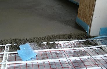 Снимка - Изливане на бетонна замазка върху тръбопровода за подово отопление